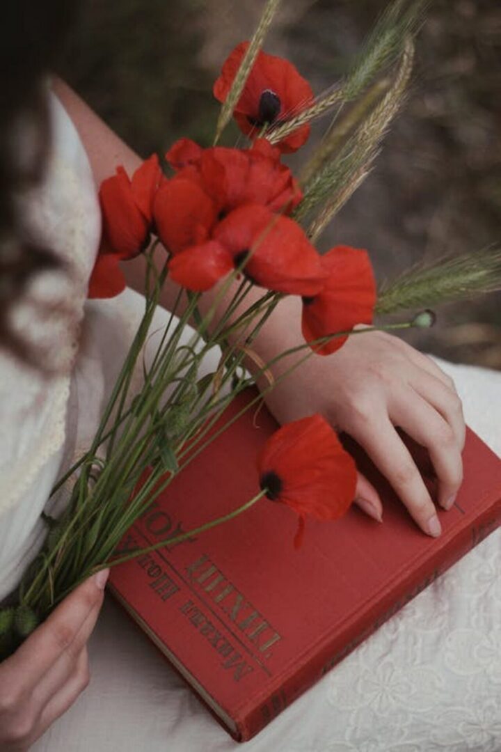 A woman holding poppies and a red book